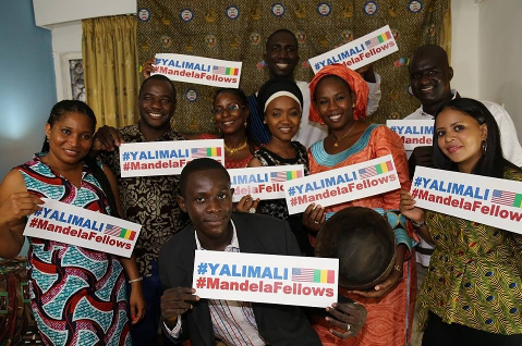 Smiling men and women holding up signs with the hastag YaliMali.