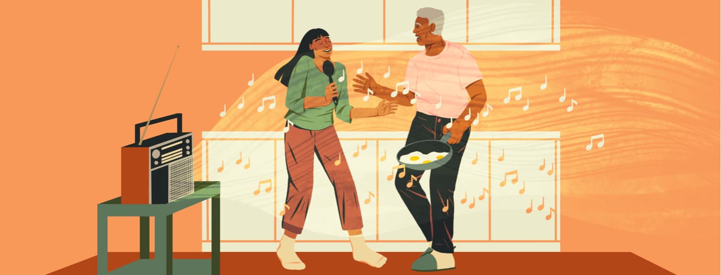 A radio plays music while two people dance in the kitchen. A woman is singing into a spoon and a man is holding a frying pan with eggs.
