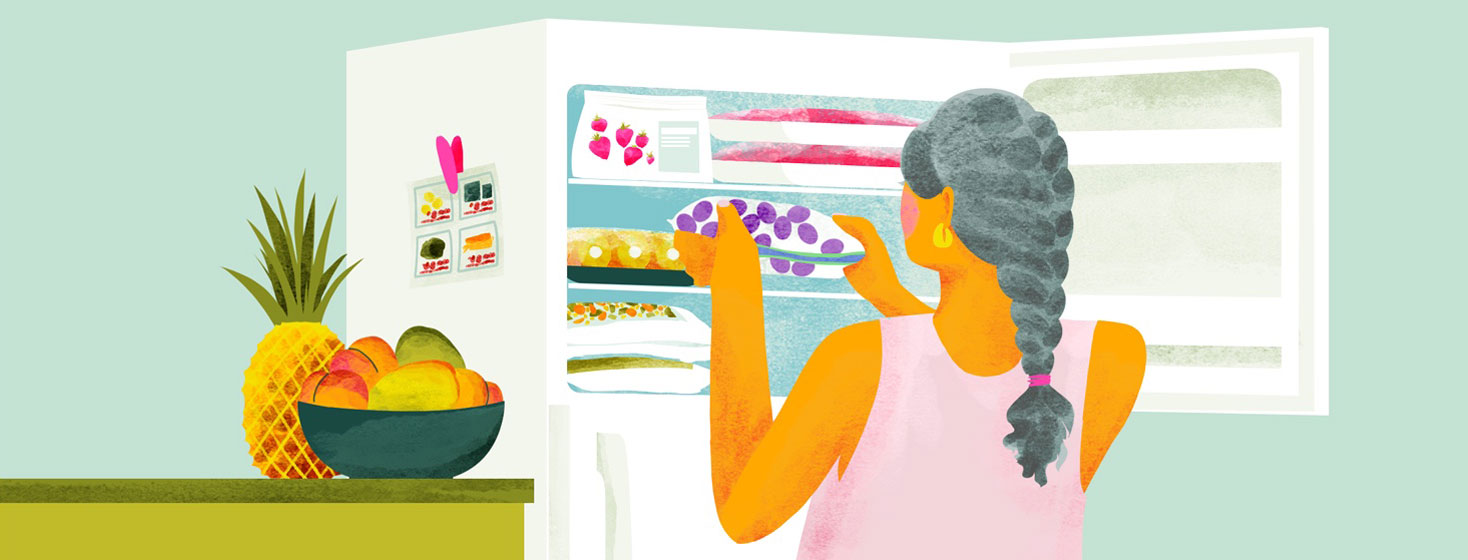 a woman puts frozen fruit in her freezer